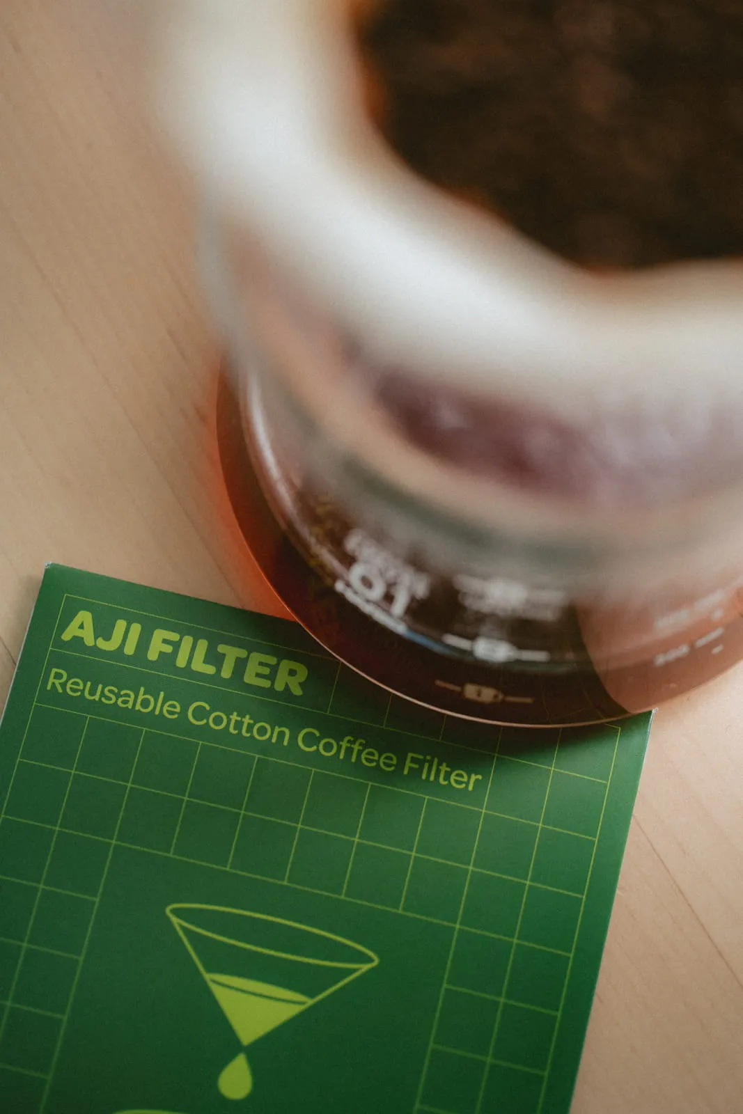 AJI Filter reusable cotton coffee filter packaging with a coffee grinder in the background