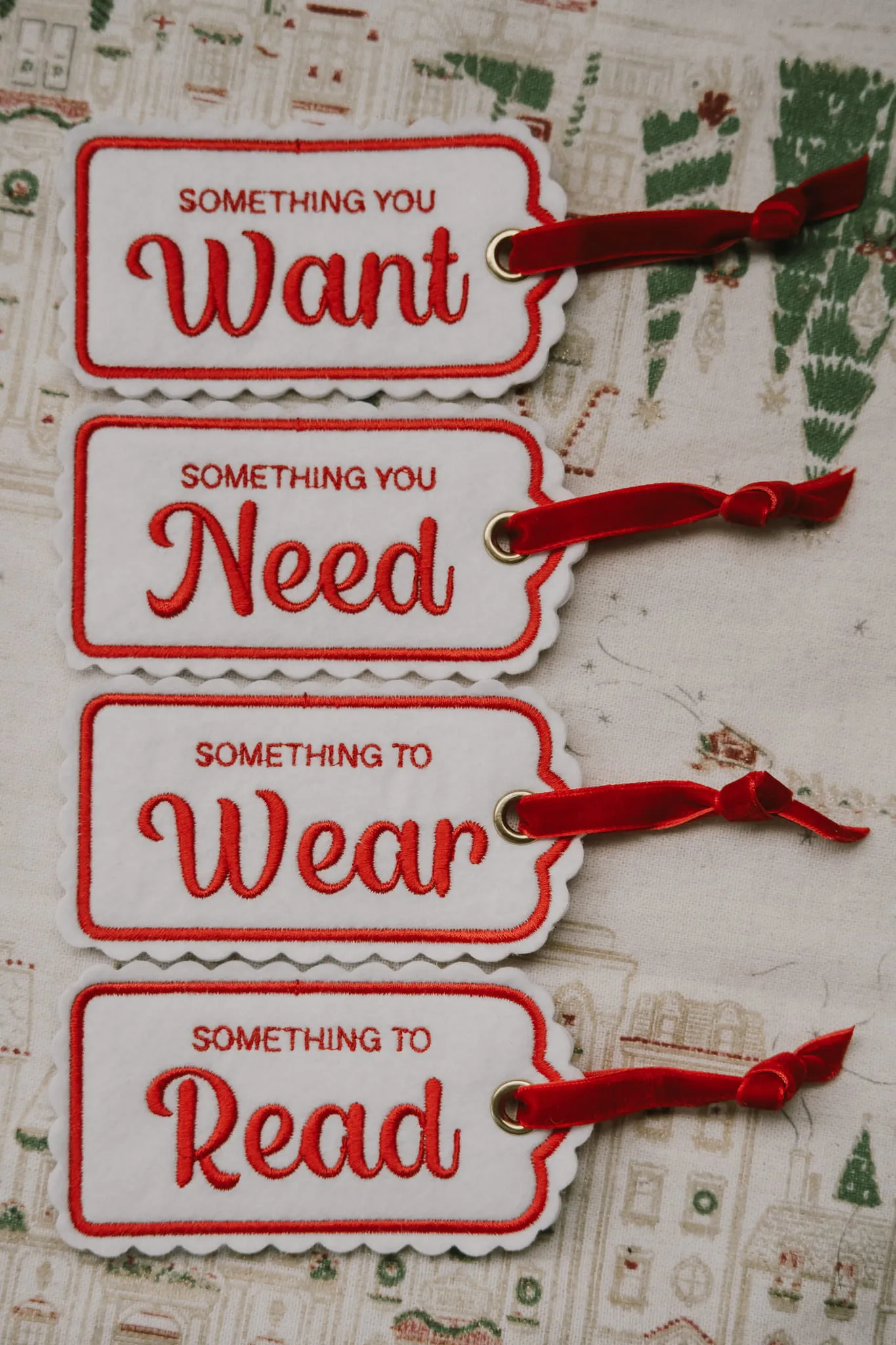 Set of four embroidered felt gift tags reading Something you Want, Something you Need, Something to Wear, Something to Read