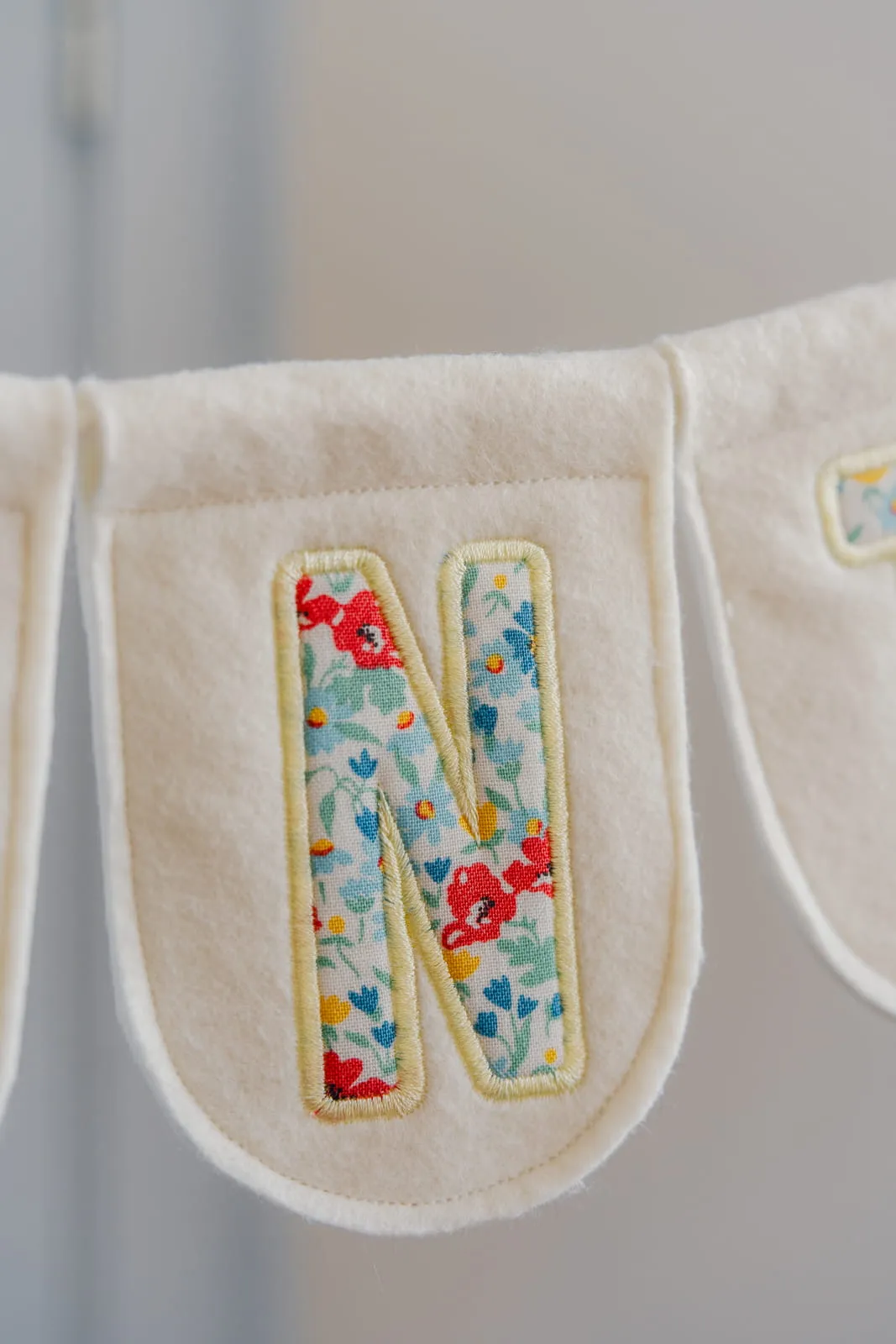 Cream felt bunting pennant with a floral fabric letter N appliqué